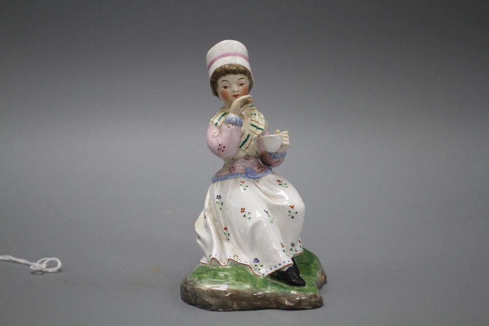 A 19th century Staffordshire figure of a seated young lady taking tea, height 13cm